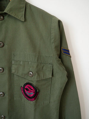 Detail of the Airman rank chevron patch on the sleeve and the squadron patch on the pocket of the OG-507 shirt.