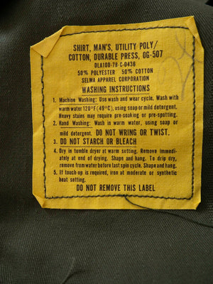 Original 1978 military label inside the OG-507 shirt, reading Shirt Man's Utility Poly Cotton Durable Press OG-507, Selma Apparel Corporation.