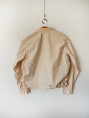 Back view of the vintage Dartmouth College Harrington jacket in light beige cotton, hung on a wooden hanger.