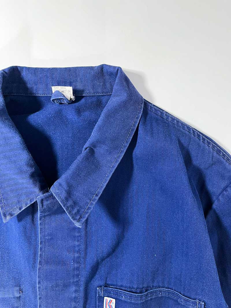 Vintage blue work jacket in hbt cotton. Quality fabric and a faded blue color given by the passage of time. Placed on a neutral white background.