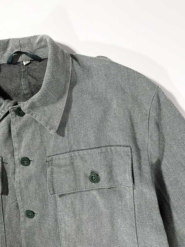 Swiss Army Denim Work Jacket produced from the 1950s to the 1990s by the Swiss Army. Color ranging from gray to greenish, made of thick, quality denim fabric. It has a workwear look but at the same time elegant, so it can be used in any situation. Positioned on a neutral white background.