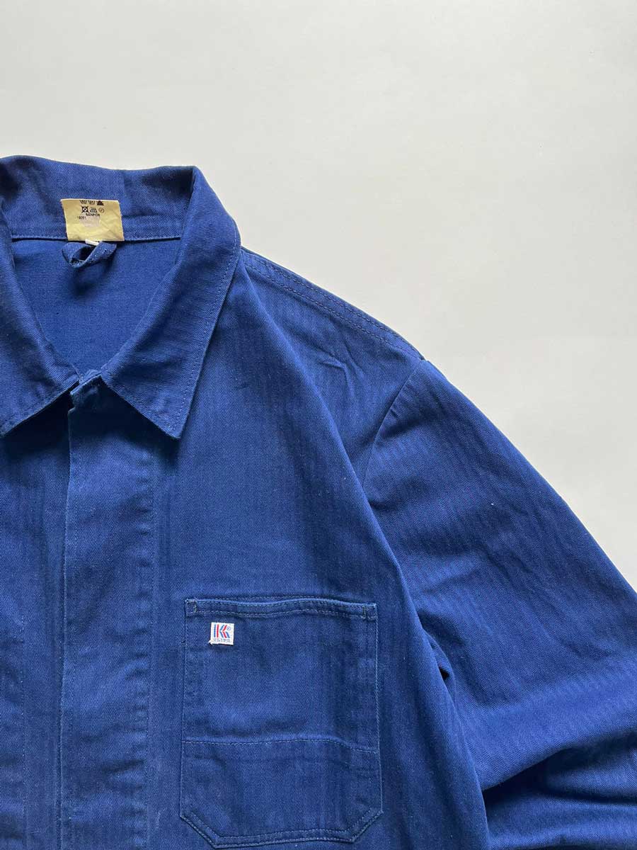Vintage blue work jacket in hbt cotton. Quality fabric and a faded blue color given by the passage of time. Placed on a neutral white background.