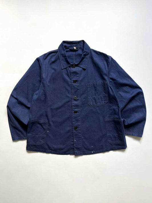 Vintage blue work jacket in hbt cotton. Quality fabric and a faded blue color given by the passage of time. Placed on a neutral white background.