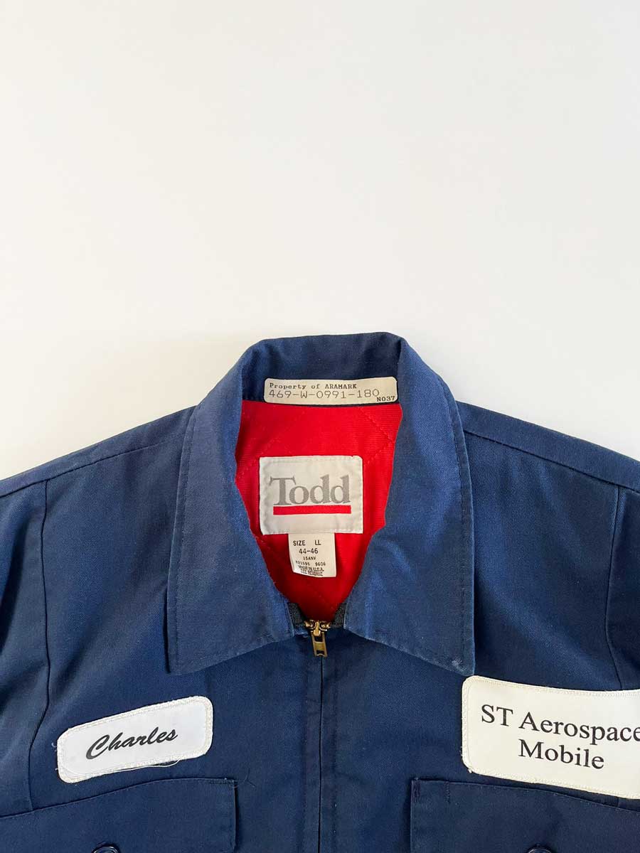 Vintage work jacket produced in the 1980s by Tod Quality fabric and perfectly maintained over time. Patch applied on the front, "Charles" e "ST Engineering". Positioned on a neutral white background.