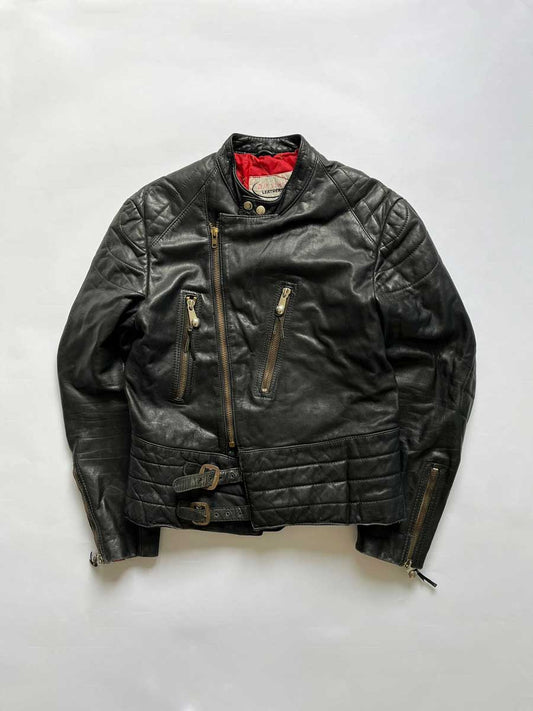 Vintage 1970s black motorcycle jacket. Genuine leather with red inner lining. Jacket placed on neutral white background.