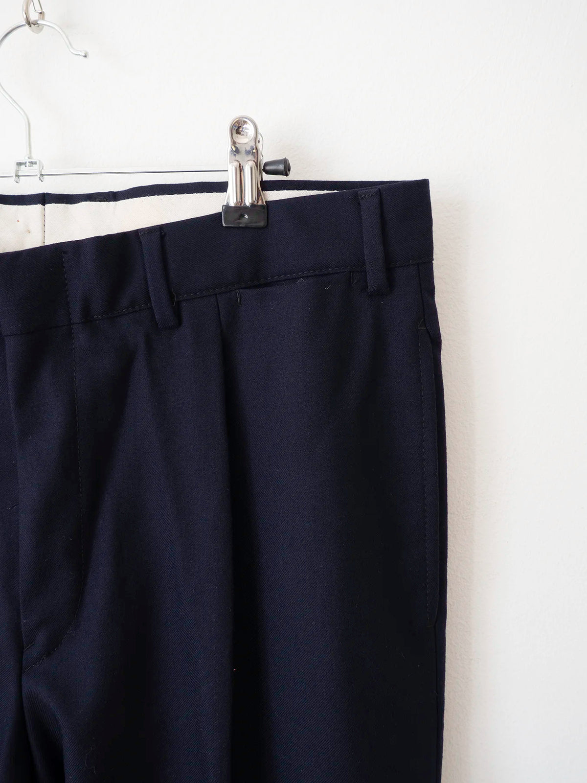 Dettaglio tasche frontali e pieghe dei pantaloni in lana blu navy