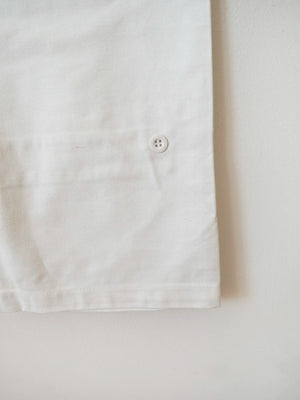 Dettaglio fondo gamba con bottone di chiusura dei pantaloni bianchi