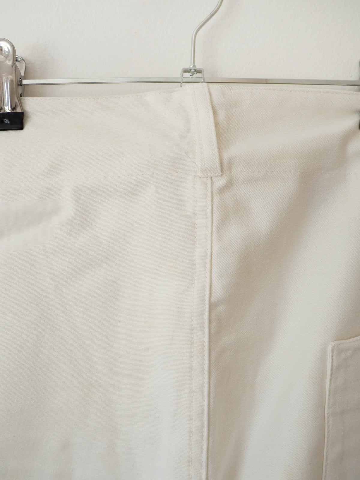 Dettaglio cucitura della vita e passante dei pantaloni bianchi