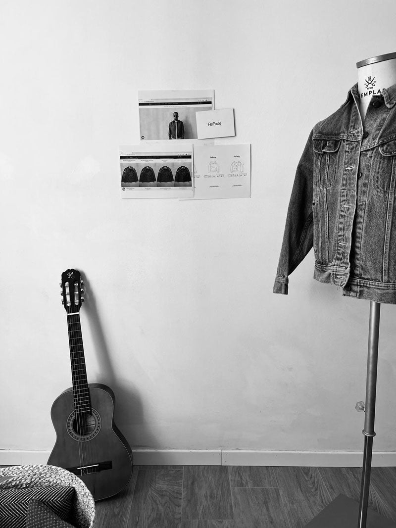 Immagine raffigurante un busto sartoriale con una denim jacket vintage, una chitarra. Muro bianco.