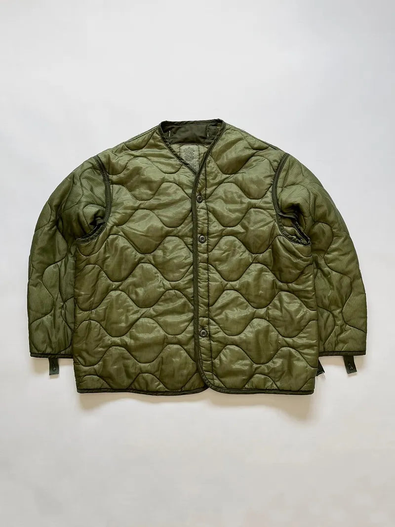 Vintage US Army M65 Liner Jacket size Large. The construction includes a front button closure and an open underarm design for greater breathability and comfort.