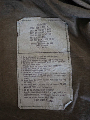 Giacca da campo M65 vintage verde oliva, vista frontale su gruccia