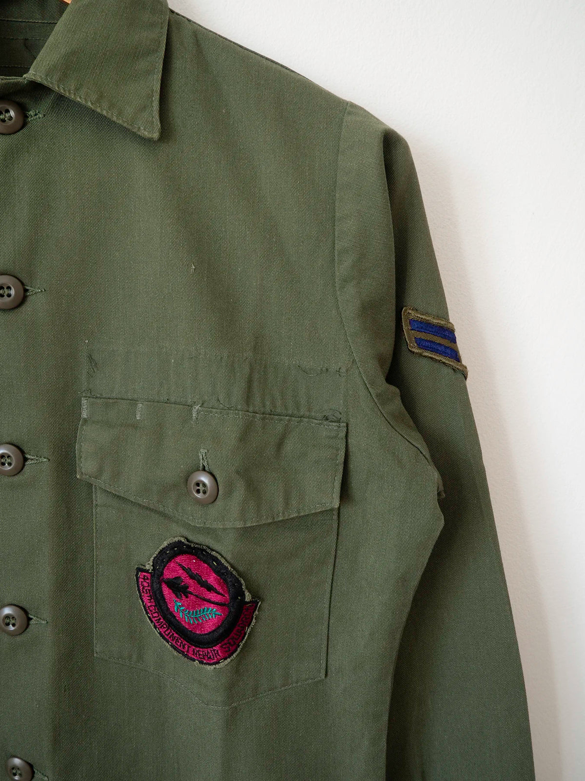 Detail of the Airman rank chevron patch on the sleeve and the squadron patch on the pocket of the OG-507 shirt.