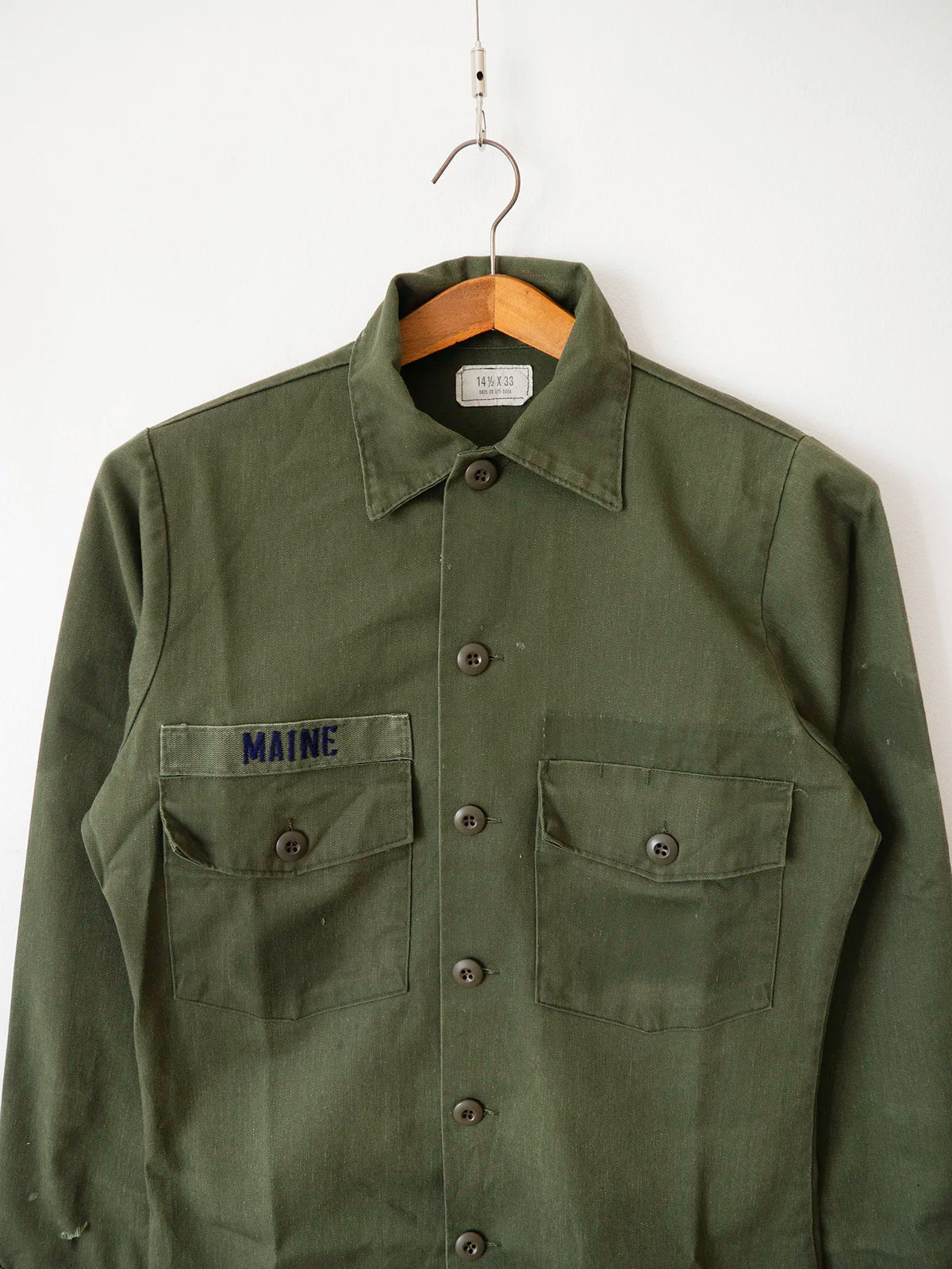 Close-up of the collar and chest pockets on the OG-507 olive green utility shirt with Maine name tape.