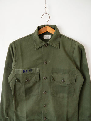 Close-up of the collar and chest pockets on the OG-507 olive green utility shirt with Maine name tape.