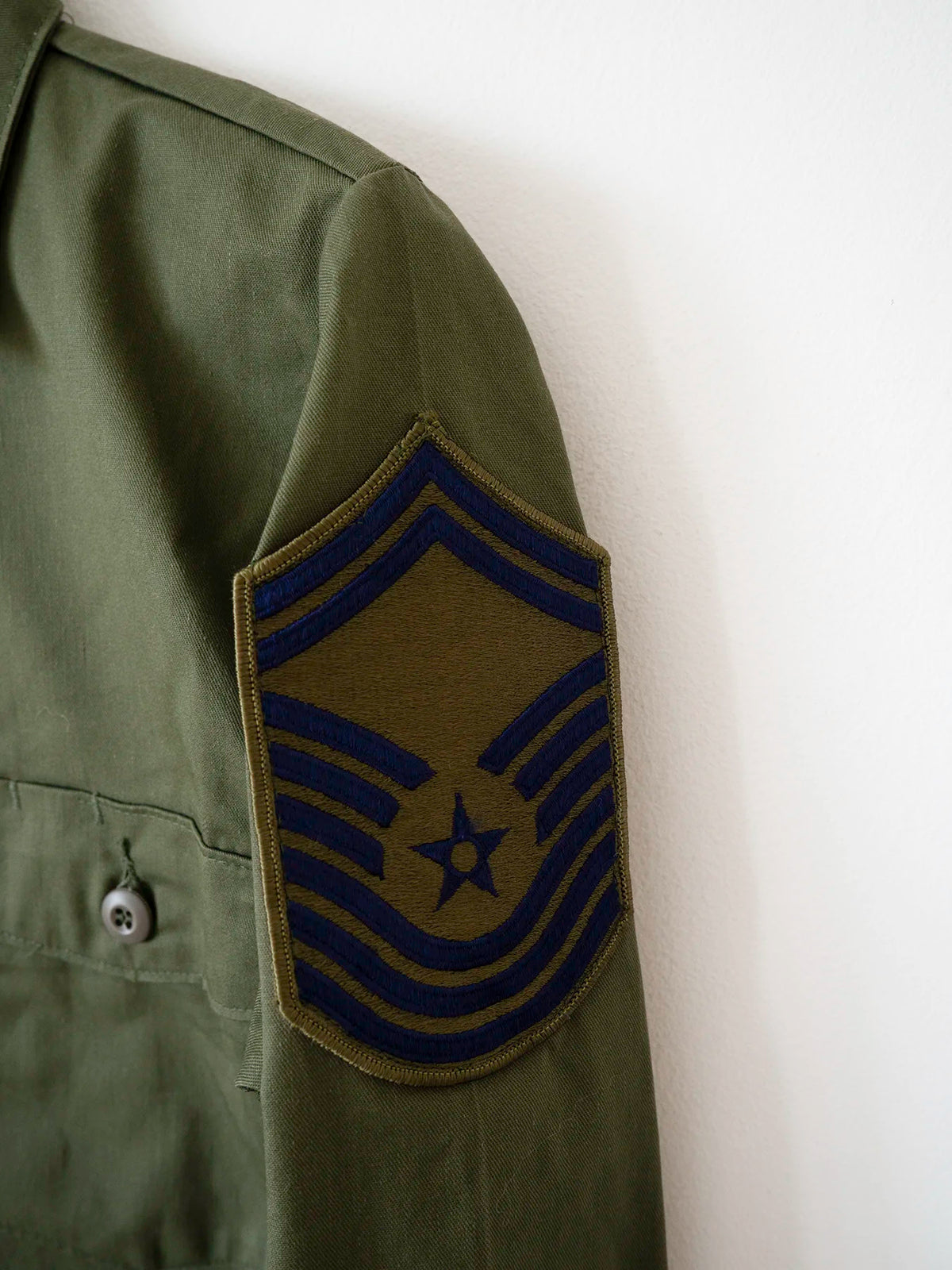 Close-up of the embroidered Chief Master Sergeant insignia on the OG-507 Air Force shirt.