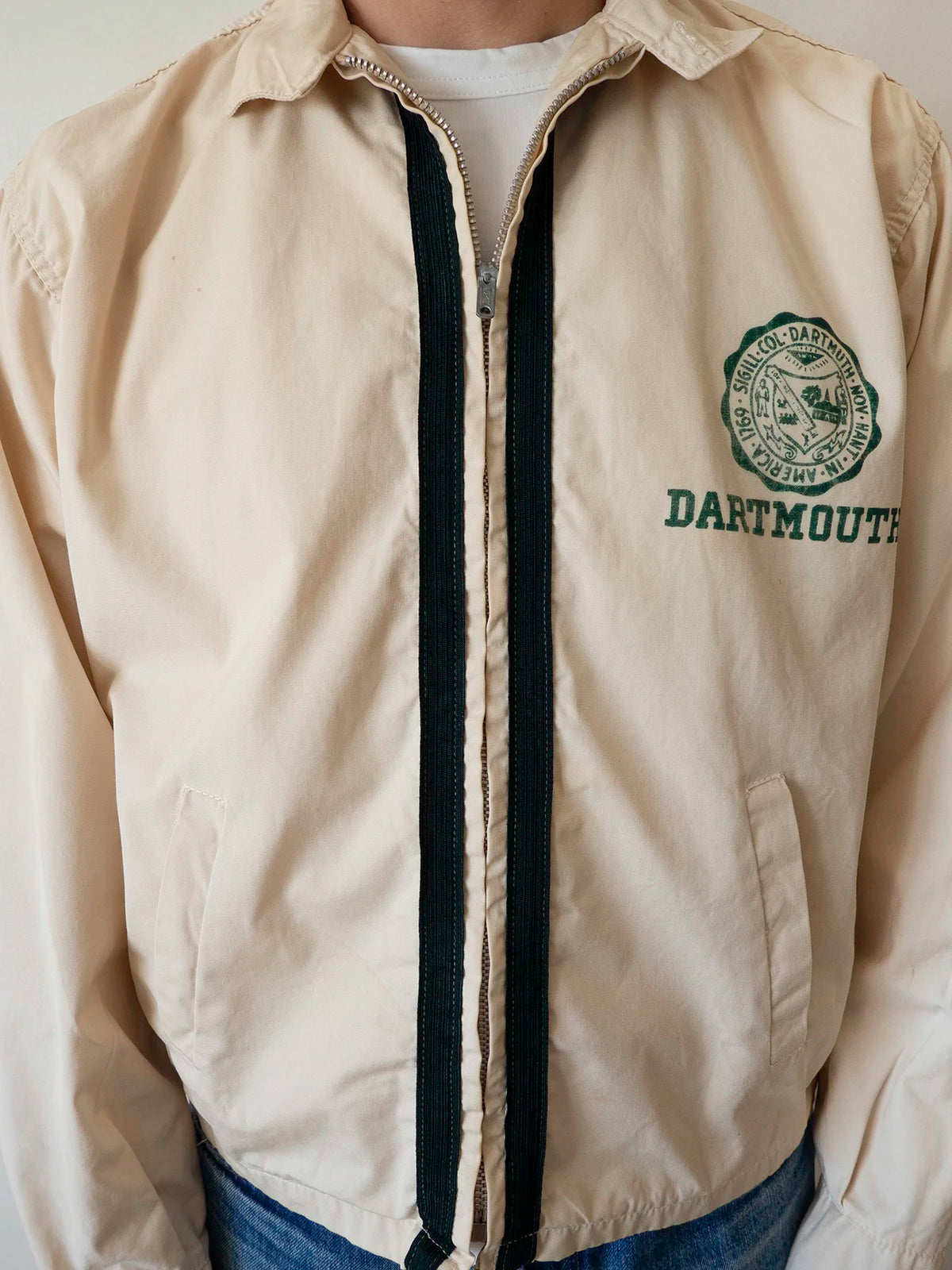 Close-up of a model wearing the Dartmouth College Harrington jacket, showing the front zip and chest seal patch.
